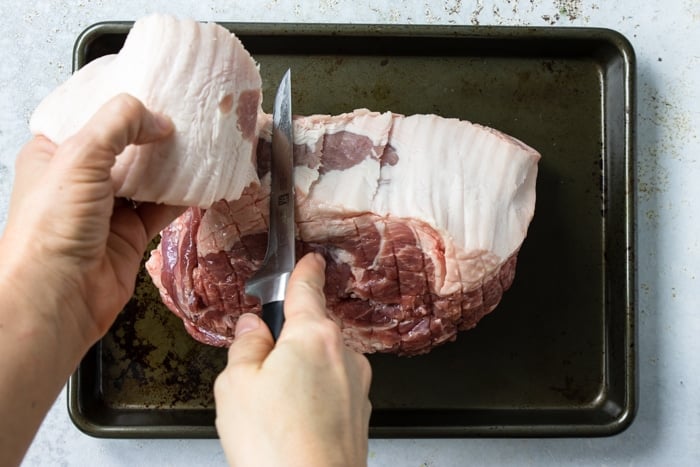 Cutting the fat cap from the pork roast with a knife