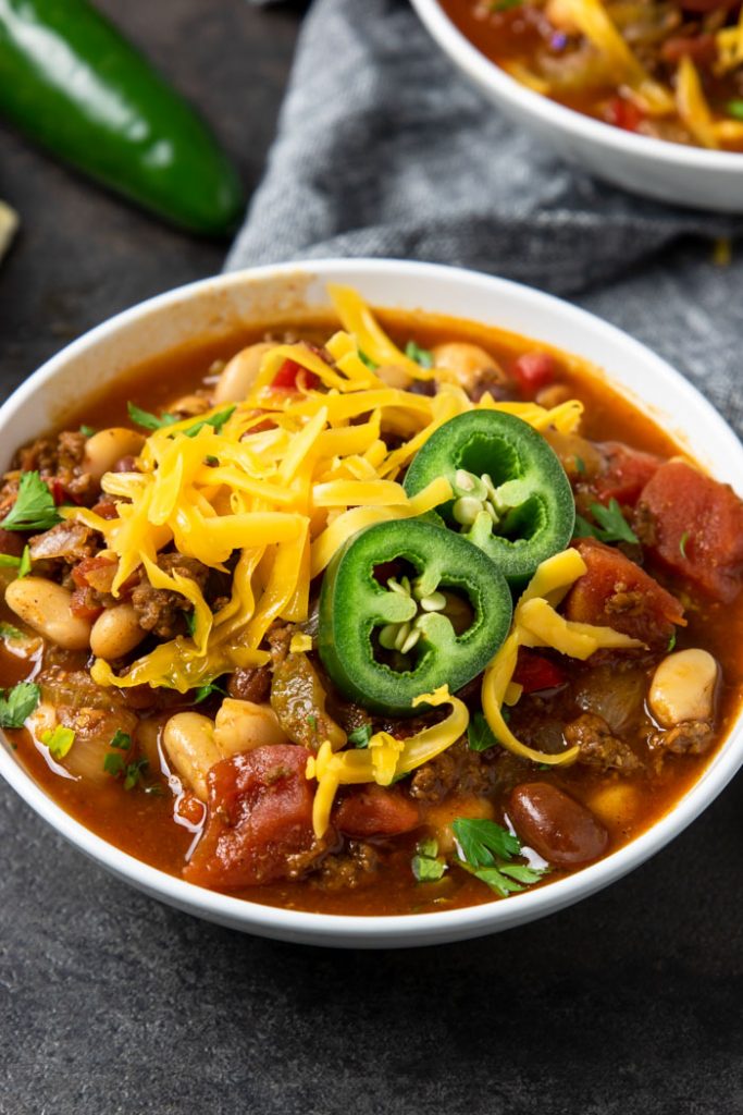 a bowl of chili topped with cheese and jalapenos
