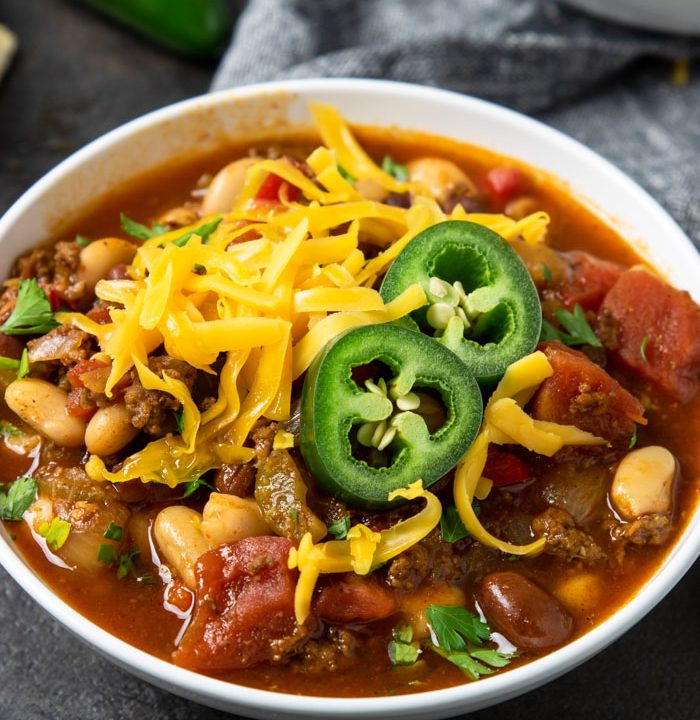 a bowl of chili topped with cheese and jalapenos