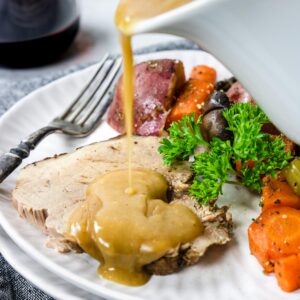 a slice of Instant Pot Pork Roast on a plate with gravy and veggies