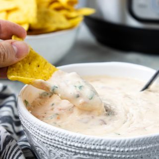 A chip being dipped into Instant Pot Queso