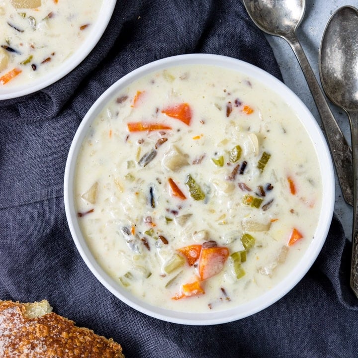 Creamy wild rice soup in a bowl with spoons to the side