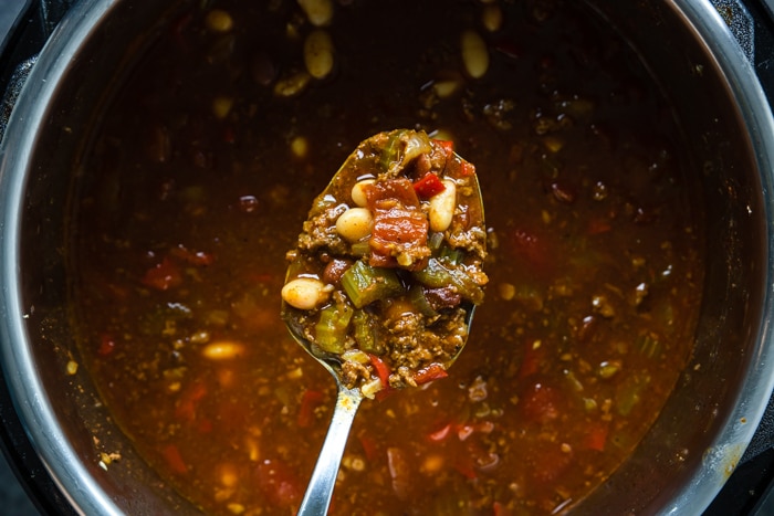 A spoonful of chili over a pot