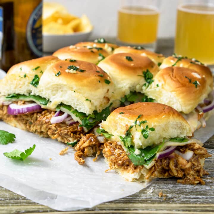 BBQ chicken Sliders on a table with two beers in the background
