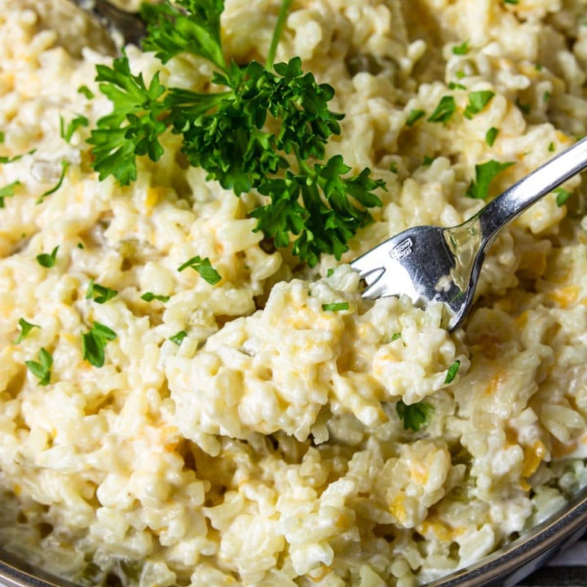 Close up of cheesy rice on a fork resting in the bowl.