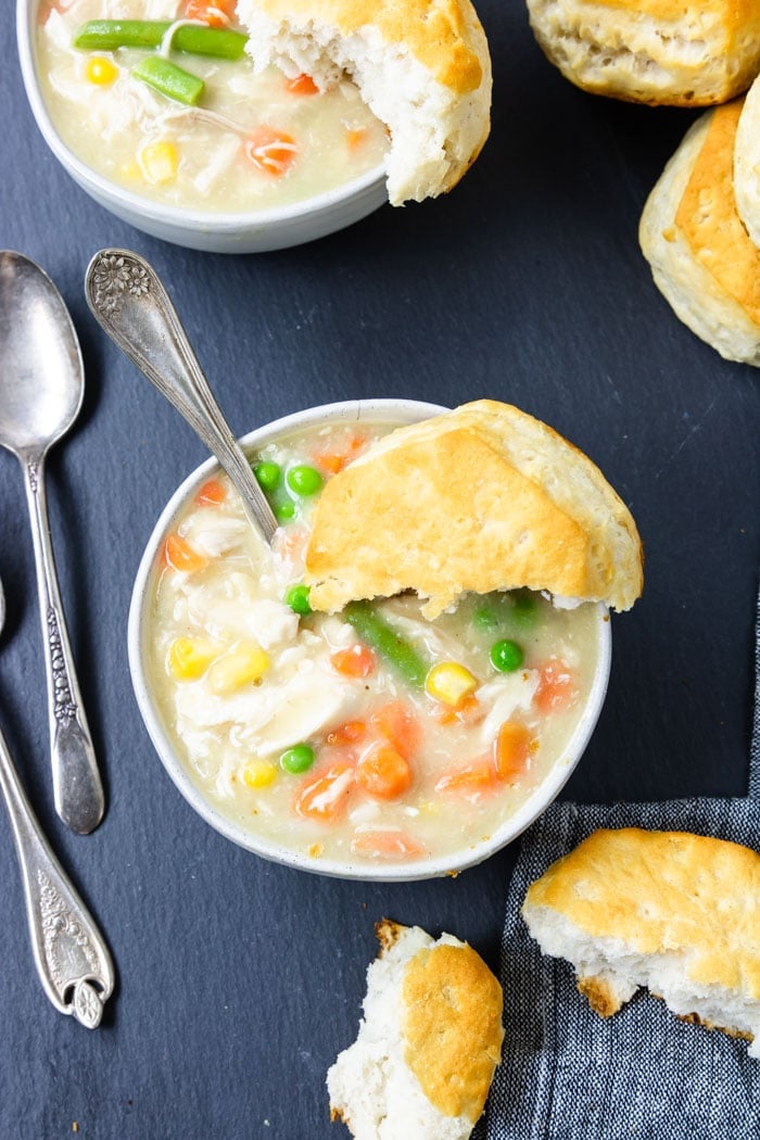 easy chicken and biscuits in a white bowl with half a biscuit on top and a spoon