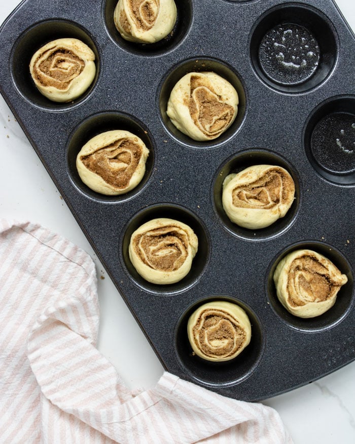 uncooked cinnamon rolls in a muffin tin
