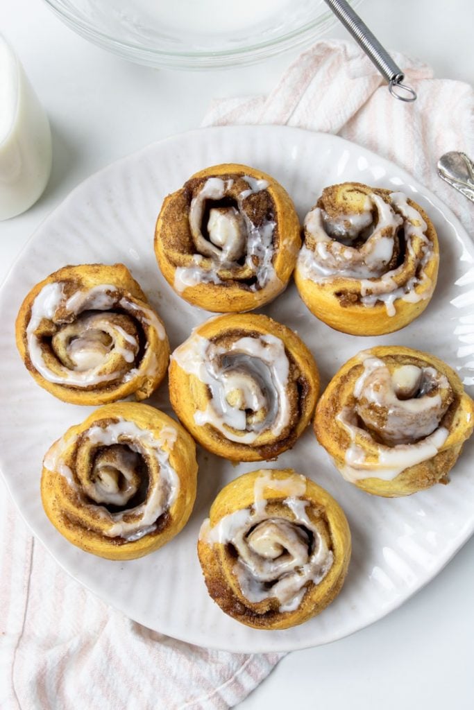 7 crescent cinnamon rolls topped with frosting on a white plate 