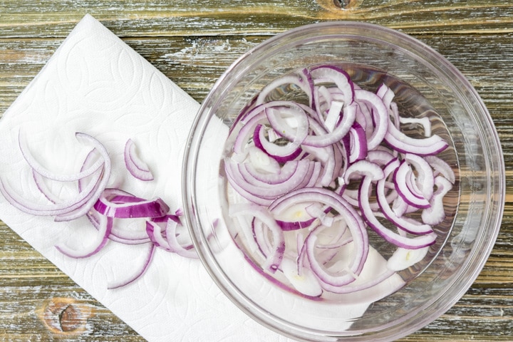 raw red onions being rinsed in water
