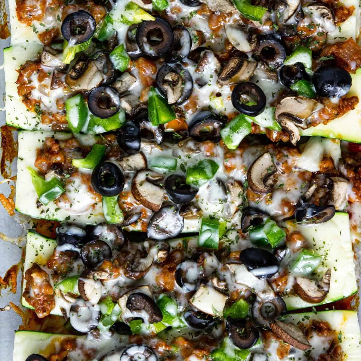 zucchini pizza boats in a row with all the toppings