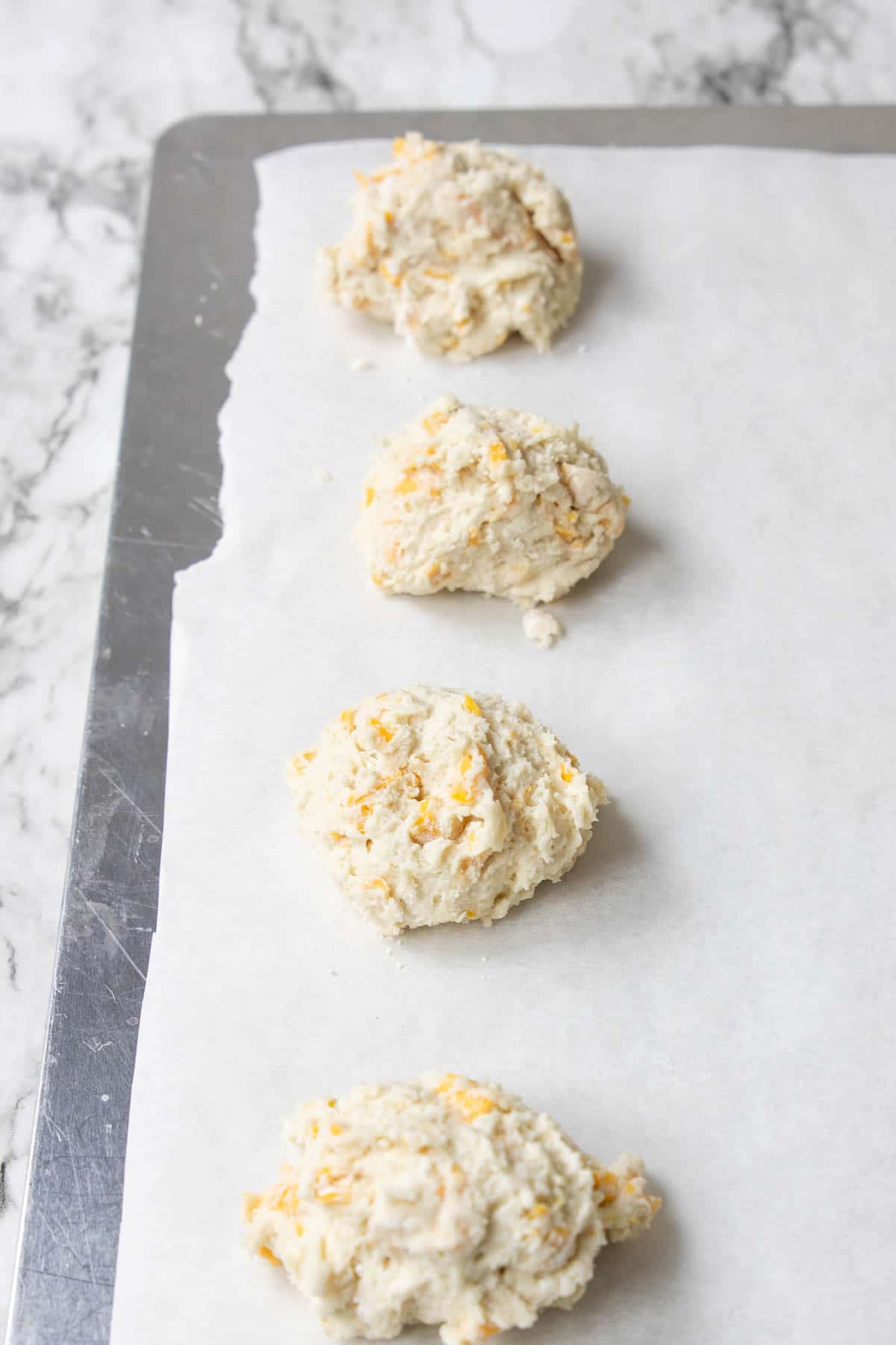garlic cheddar biscuits dropped on a cookie sheet lined with parchment