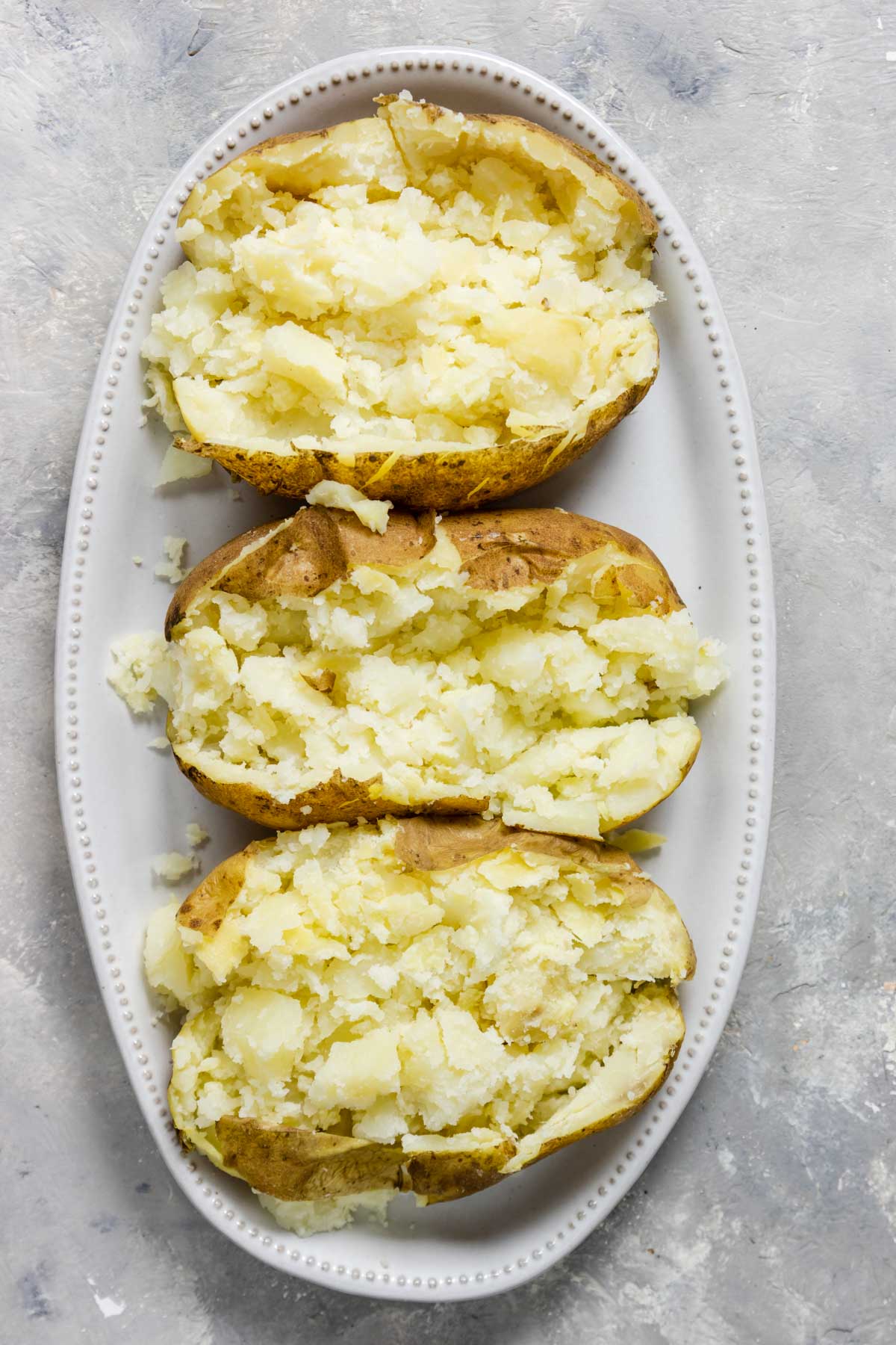 tender and fluffy instant pot baked potatoes cut open on a plate