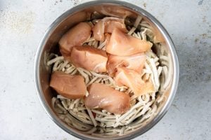 Step 4: Lay the quartered chicken breasts on top of the noodles