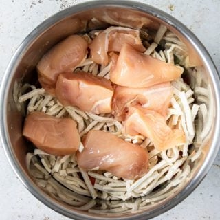Step 4: Lay the quartered chicken breasts on top of the noodles