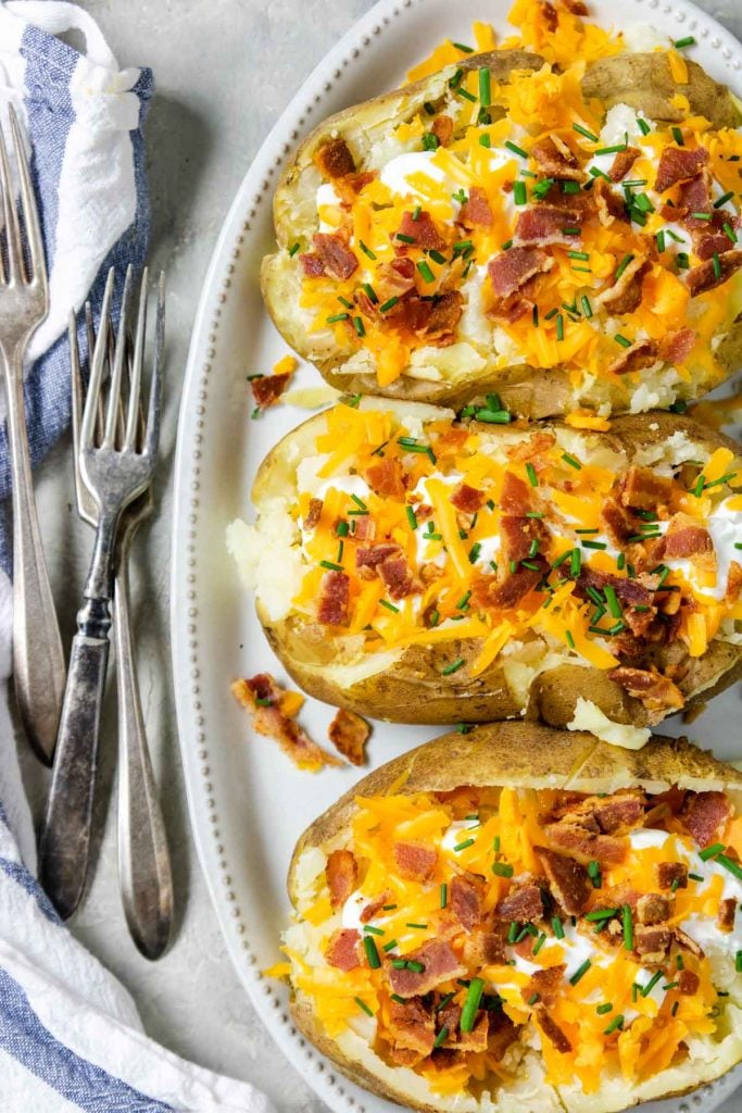 Instant Pot Baked Potatoes on a plate loaded with sour cream cheese bacon and chives