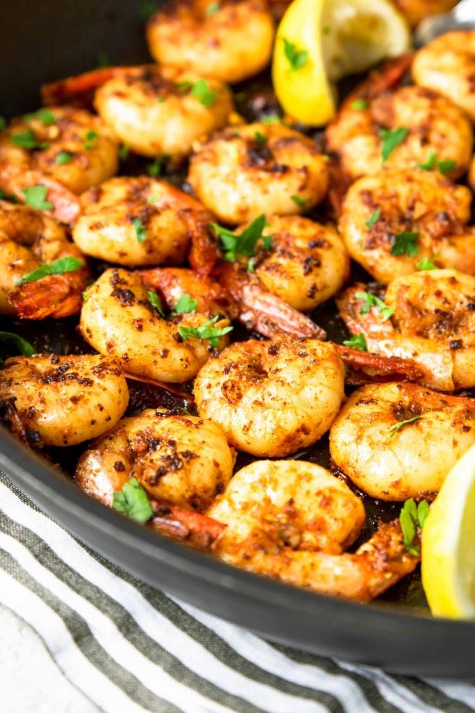 cajun shrimp cooked in a skillet with lemon wedges and parsley ganish