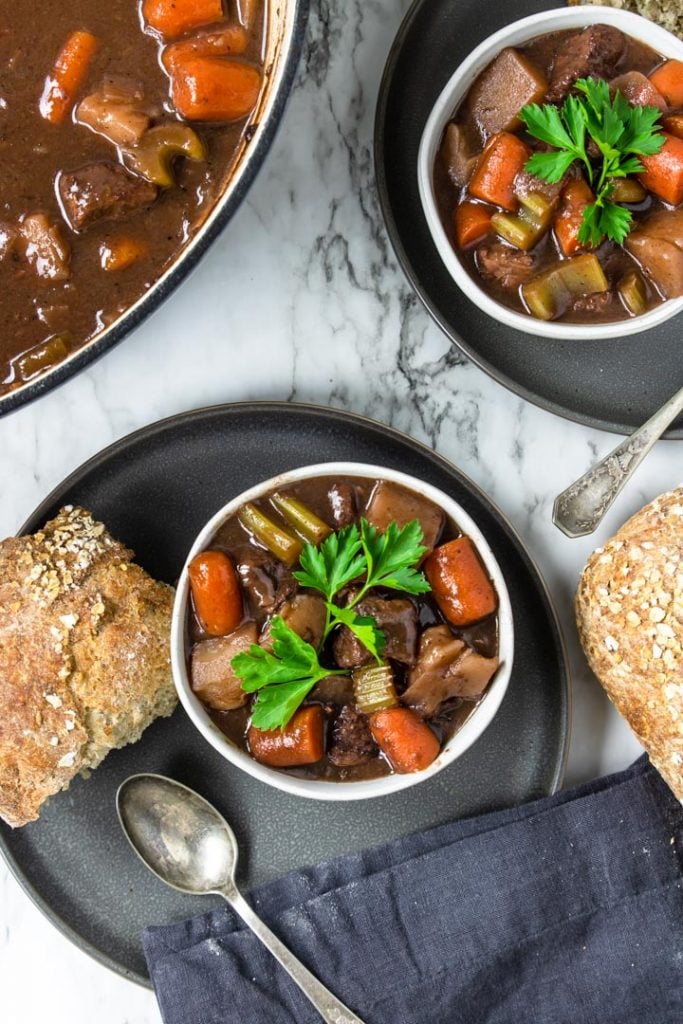 two bowls of beef stew with red wine served with crusty bread