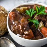 beef stew with red wine in a white bowl garnished with parsley
