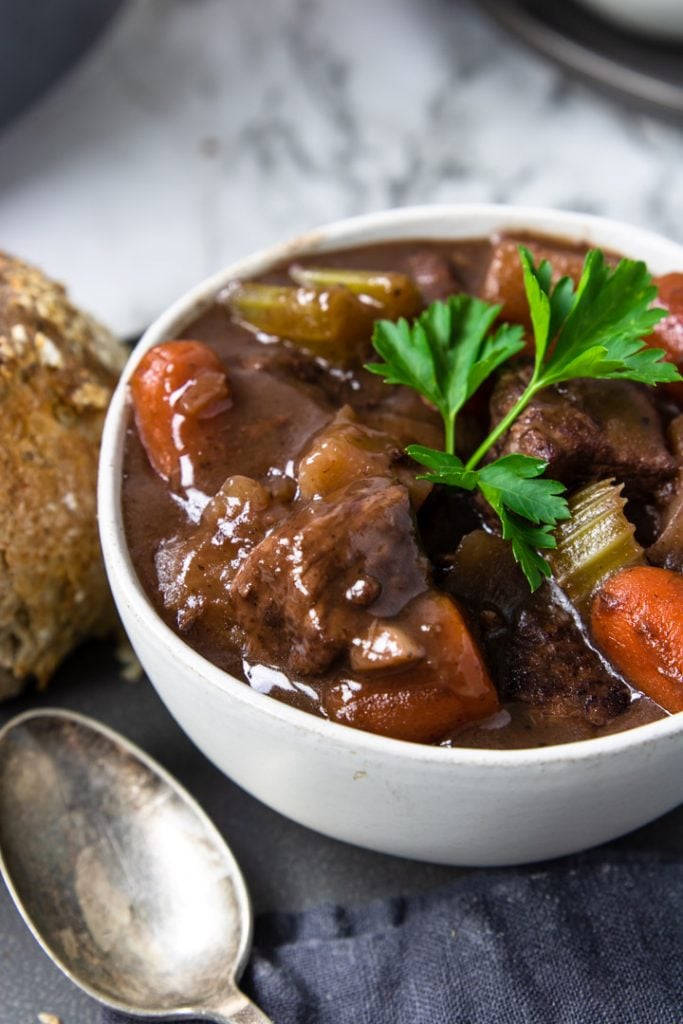 beef stew with red wine in a white bowl garnished with parsley