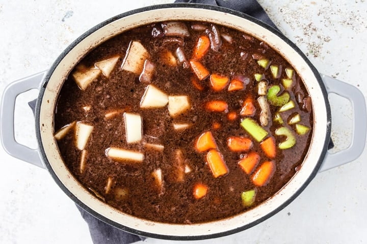 Dutch oven with red wine, beef broth, potatoes, celery and carrots