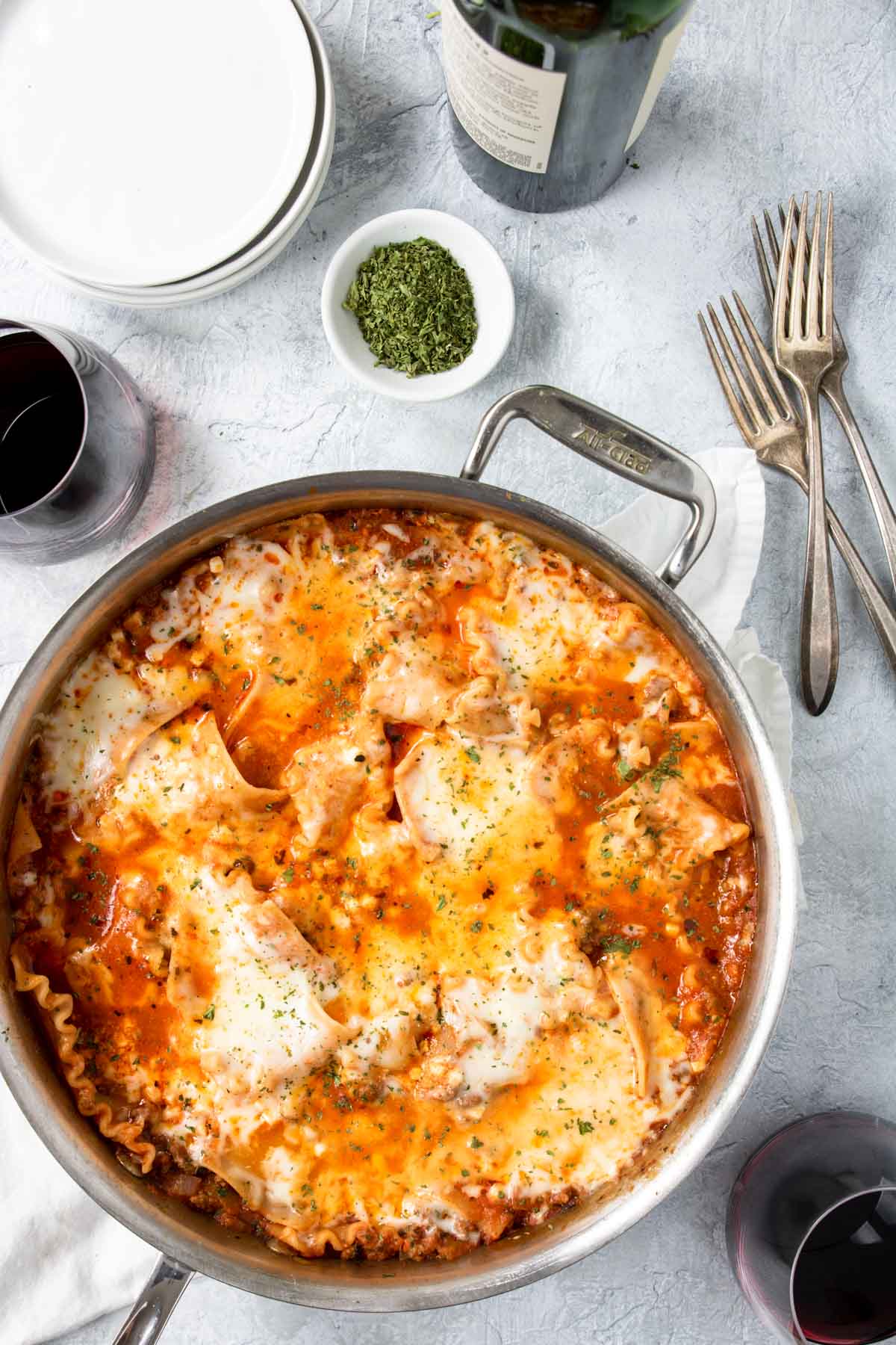 tablescape with an all clad skillet with lasagna, plates and red wine