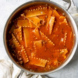 lasagna noodles nestled in sauce in a skillet