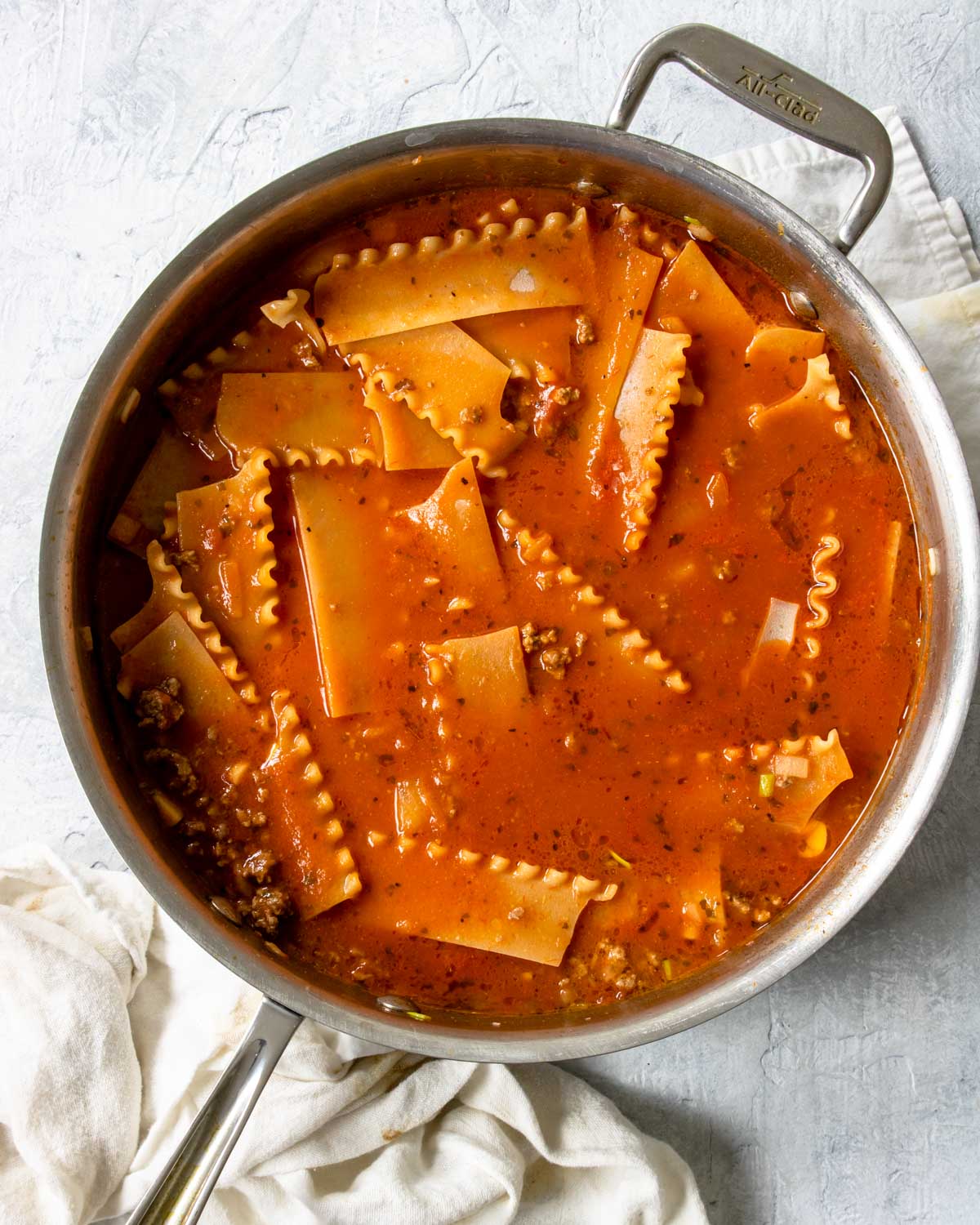lasagna noodles nestled in sauce in a skillet