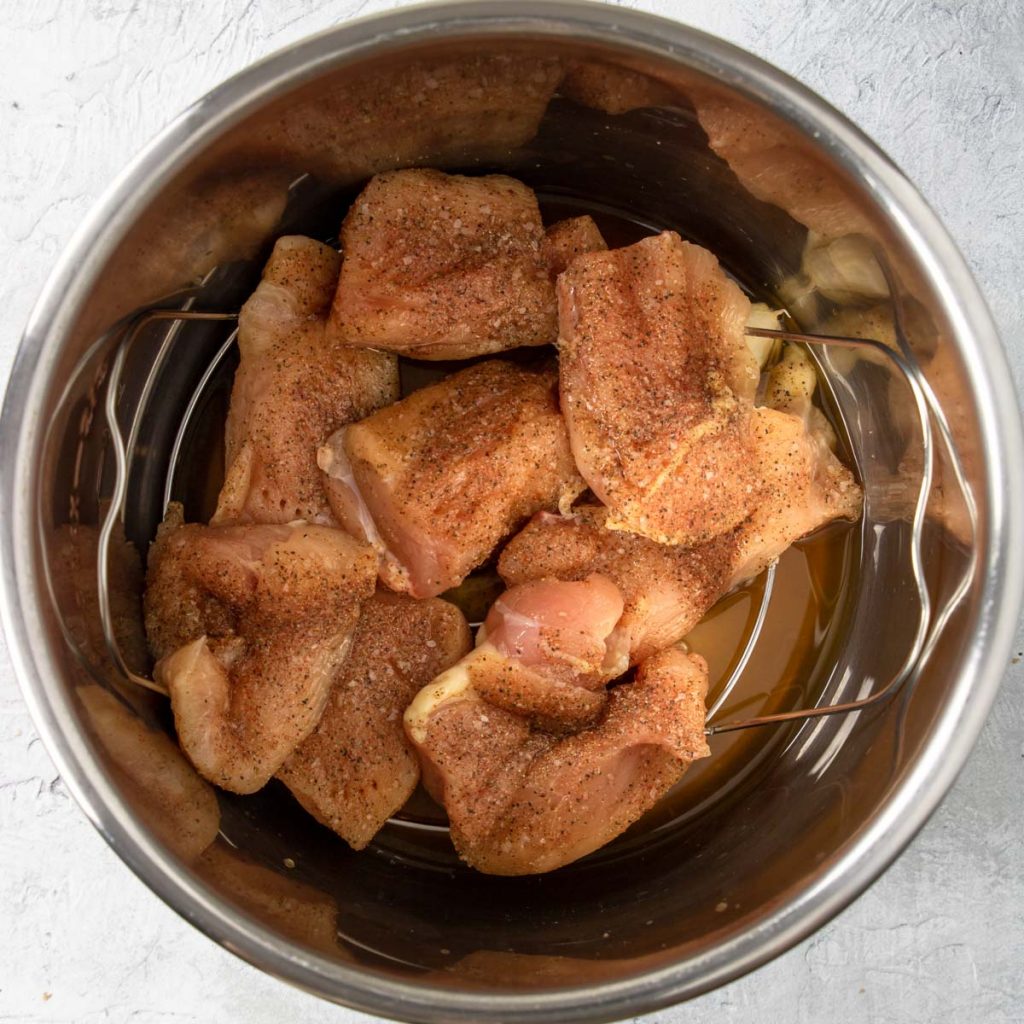 BBQ dry rub coated chicken pieces in the bottom of the instant pot