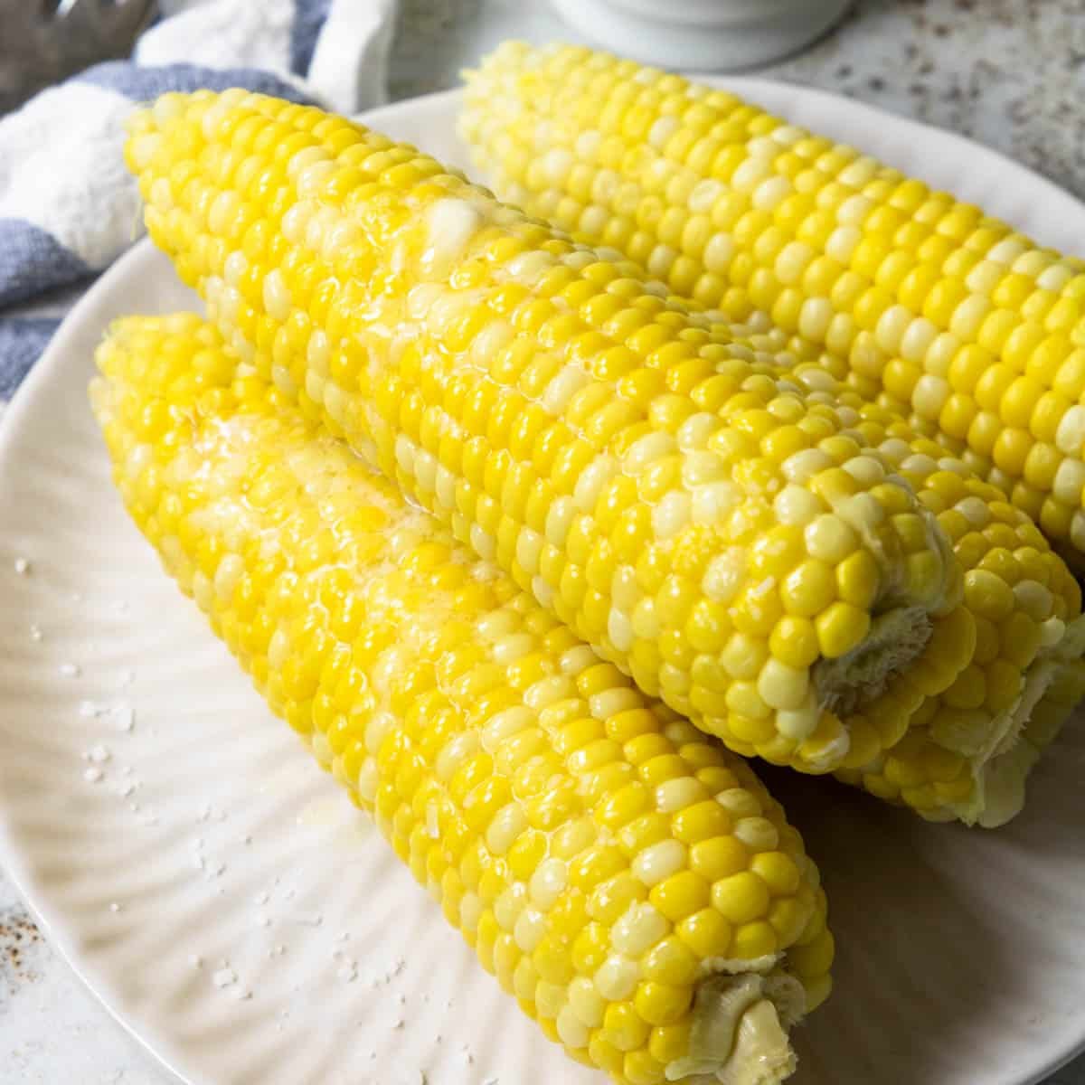 a plate of ears of corn with butter and salt