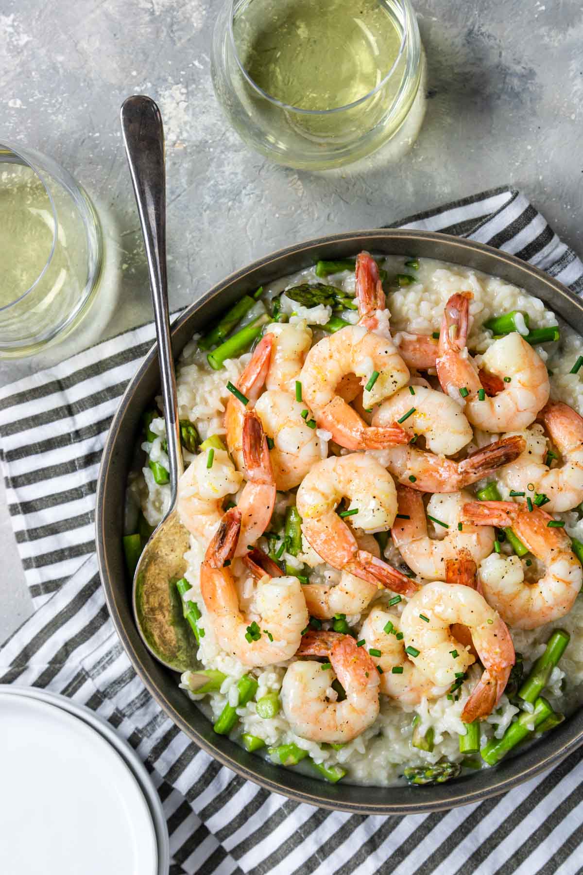 Instant Pot Shrimp Risotto with asparagus in a bowl with two glasses of white wine