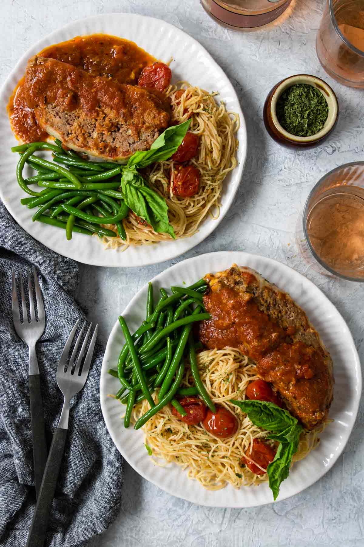 Italian Meatloaf dinner served on white plates with spaghettini and green beans