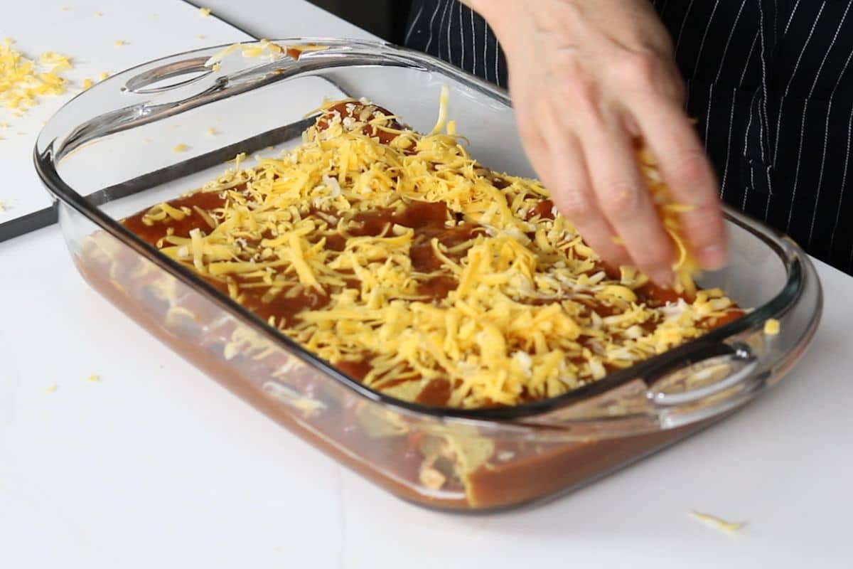 a pan of chicken enchiladas with sauce and cheese on top