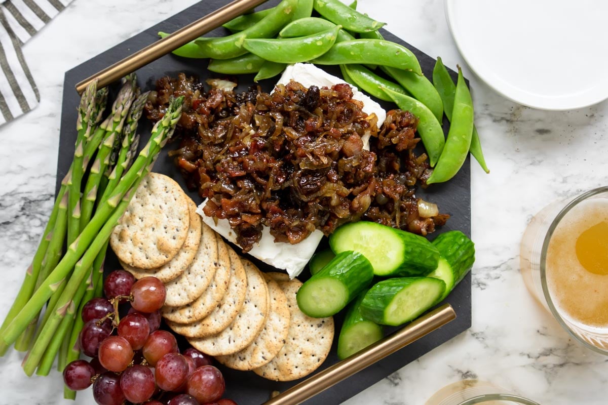 charcuterie board with veggies, crackers, grapes and cream cheese with warm bacon jam