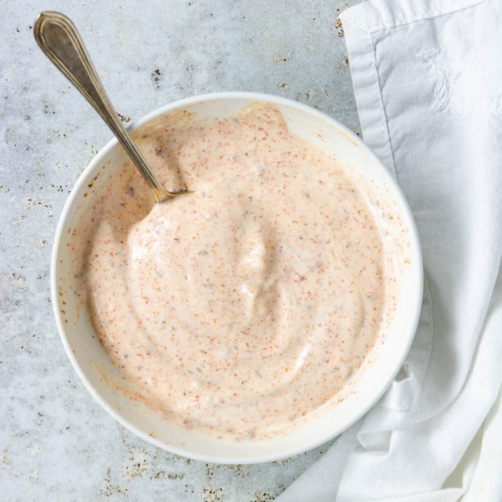 homemade cajun aioli in a white bowl with a spoon