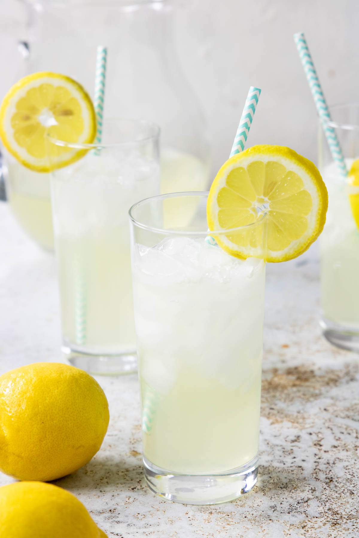 fresh squeezed lemonade in a glass with a lemon wheel and a blue paper straw