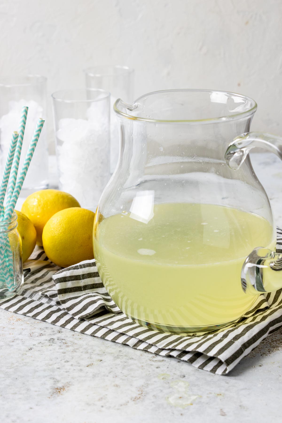 homemade lemonade in a glass pitcher with lemons to the side