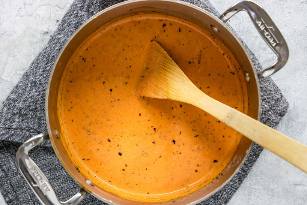 Tomato Cream Sauce in a pot with a wooden spoon