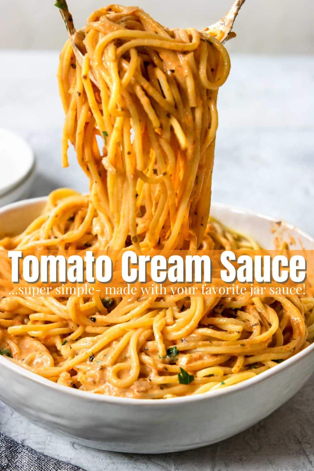Spaghetti coated in a tomato cream sauce being served from a large bowl