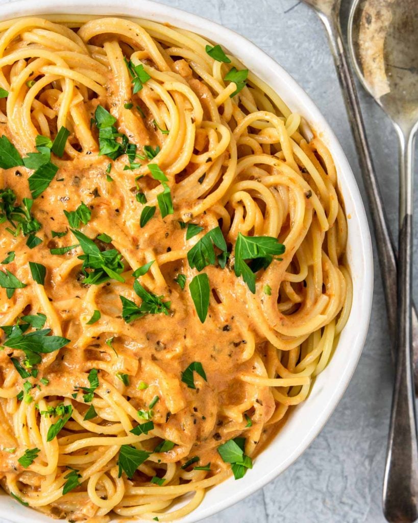 Spaghetti in a white bowl with creamy tomato sauce