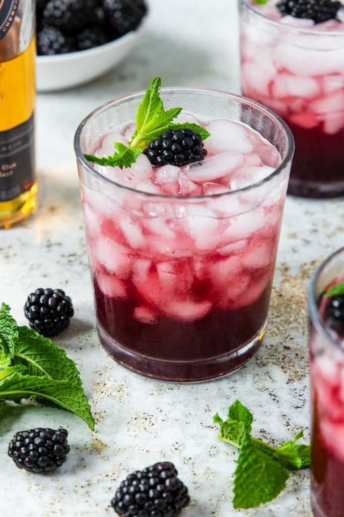 Blackberry Tequila Smash cocktail in a glass with crushed ice and garnished with mint and blackberries