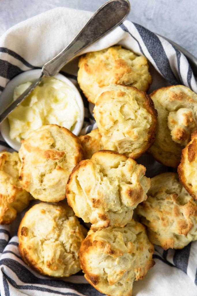 a basket full or drop biscuits with a bowl of butter