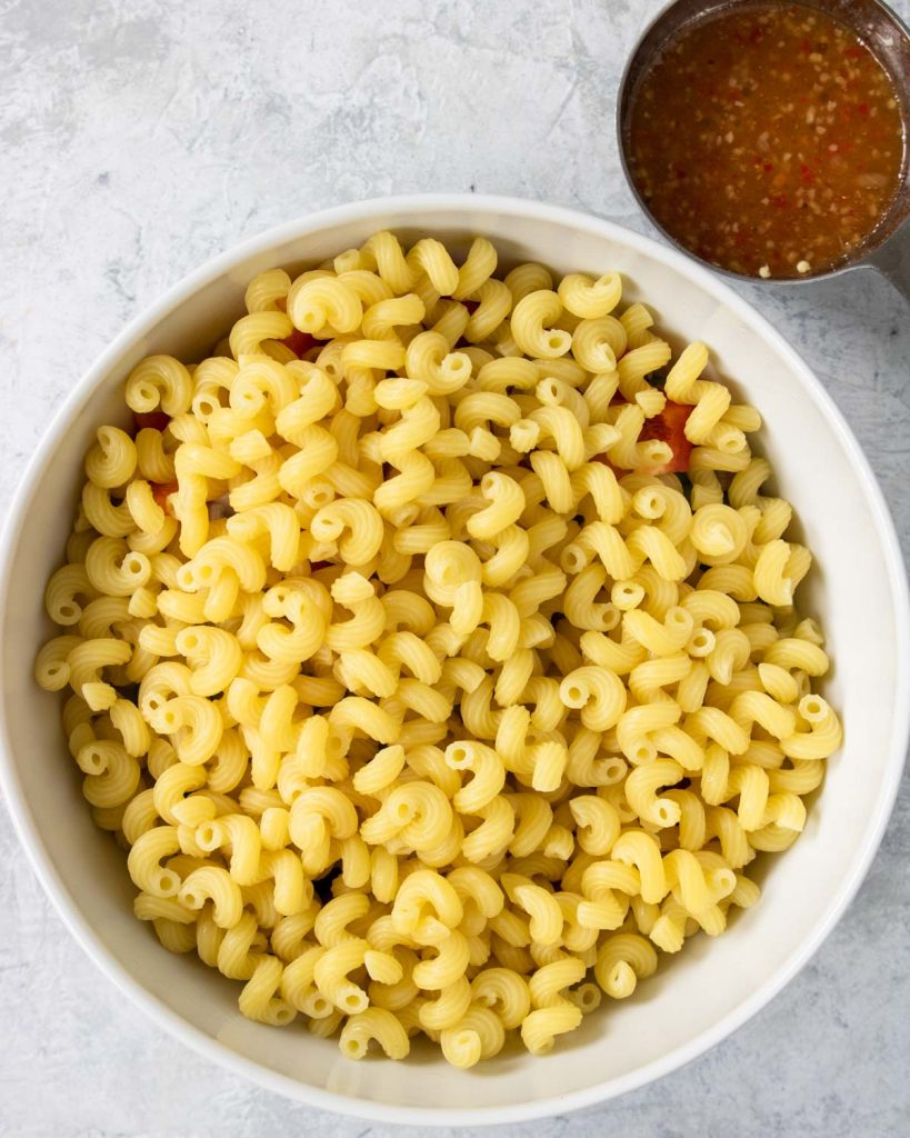 cavatappi pasta over top of the veggies in a white bowl