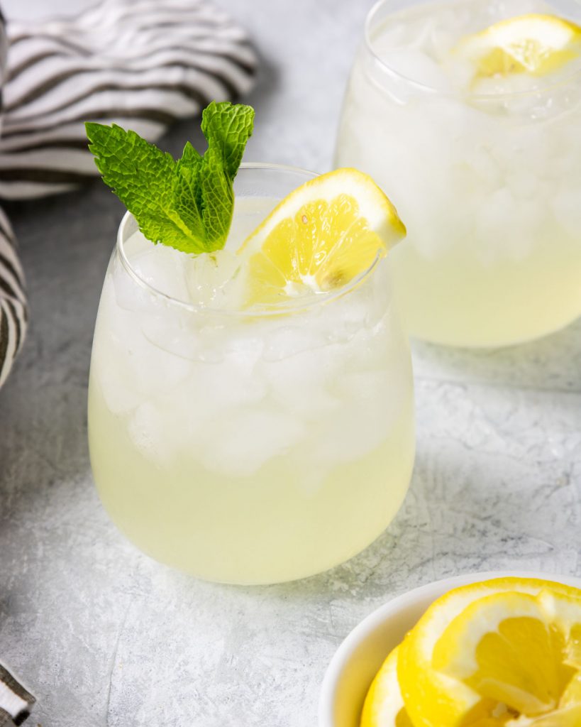 vodka with fresh lemonade in a small glass with a mint sprig and fresh lemon