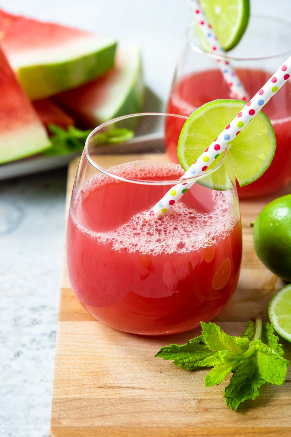 watermelon juice in a glass with a straw and a lime wheel on the side of the glass