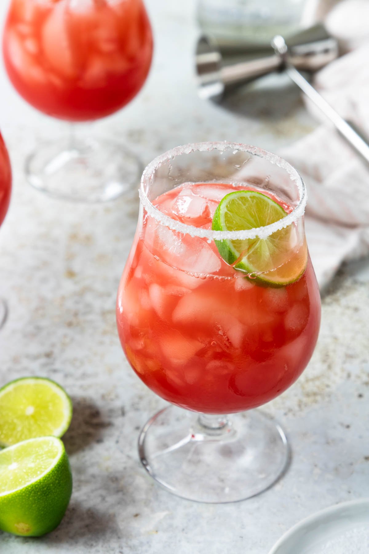 a glass of fresh watermelon margarita rimmed with sugar and salt and garnished with a lime