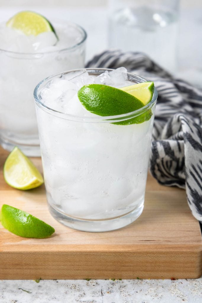 A glass filled with ice, tequila and soda and topped off with two limes