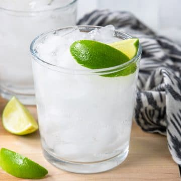 a cocktail glass filled with ice, tequila, and soda water, topped off with two lime wedges