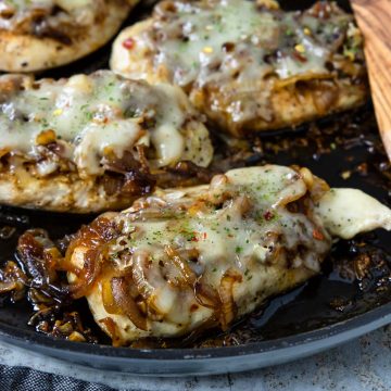 chicken breasts topped with an onion jam and melted cheese, in a skillet