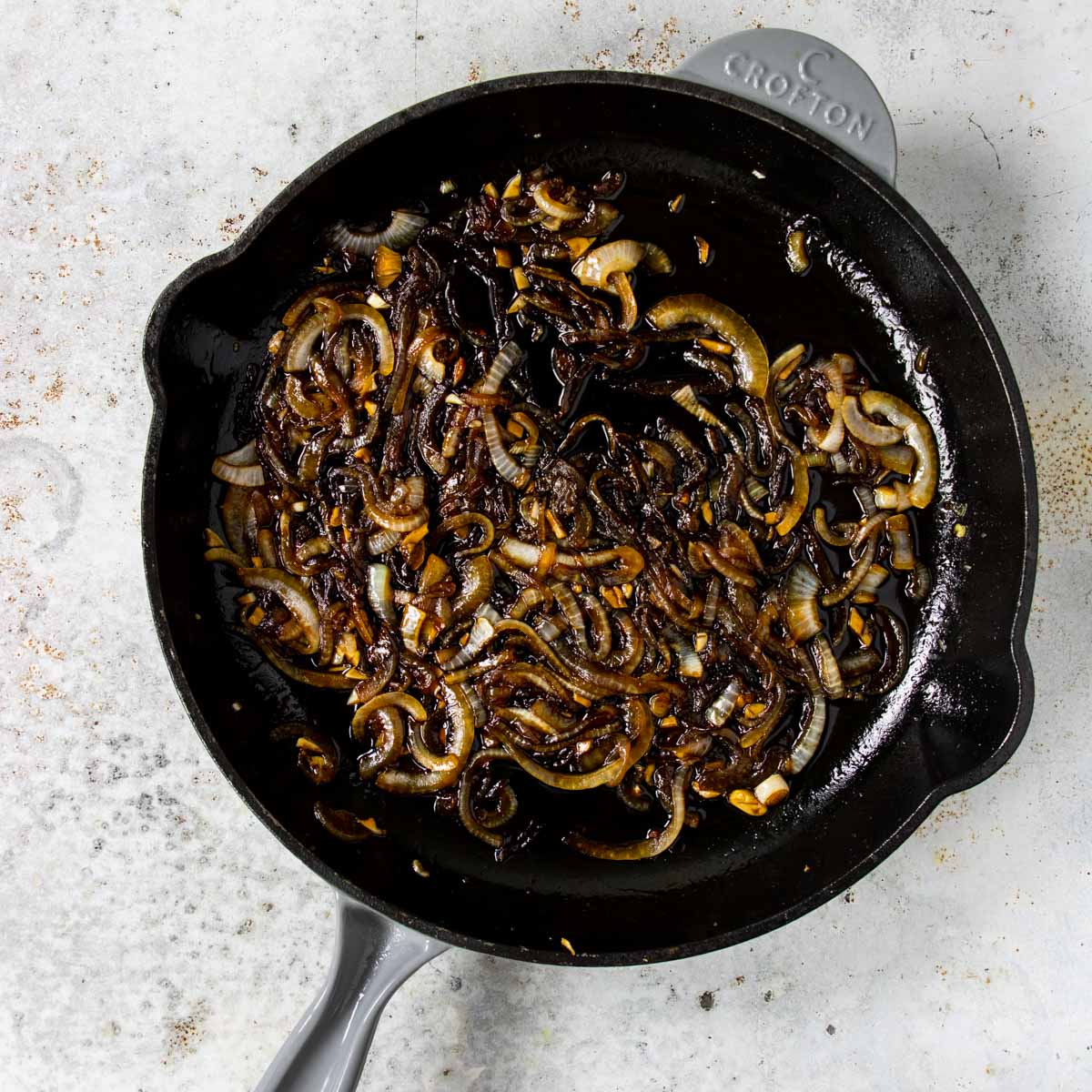 A skillet with carmalized onions in a brown sweet and savory syrup