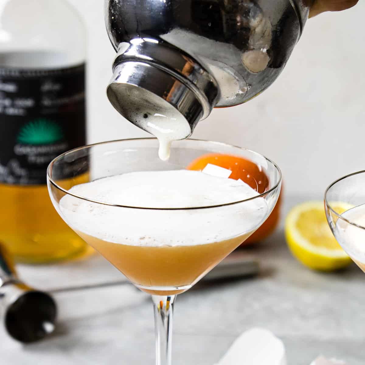 pouring a frothy cocktail from a cocktail shaker